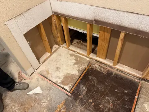 Bathroom with the wall opened to the studs and the wet subfloor exposed