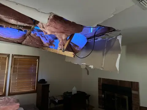 Ceiling opened with wet insulation hanging down in a living room