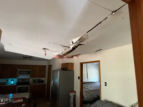 Sagging ceiling split open across a kitchen and living area