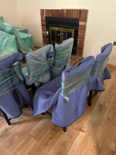 Dining chairs wrapped in moving blankets and plastic to protect them