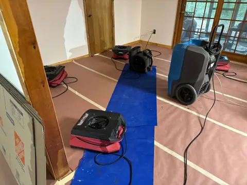 Dehumidifier and air movers on taped floor protection by a doorway