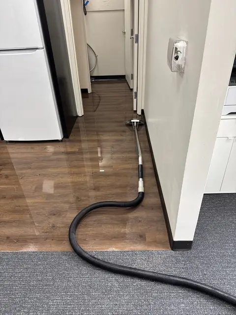 Extraction hose on a wet vinyl floor in an office hallway