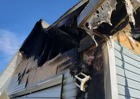 Charred roof eaves and melted siding on the outside of a house after a fire