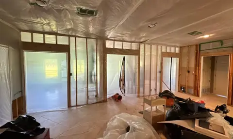 Room taken down to the wall studs with plastic sheeting during water damage repair