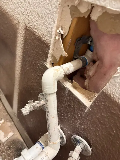 Laundry supply pipes exposed through an opening cut in the wall