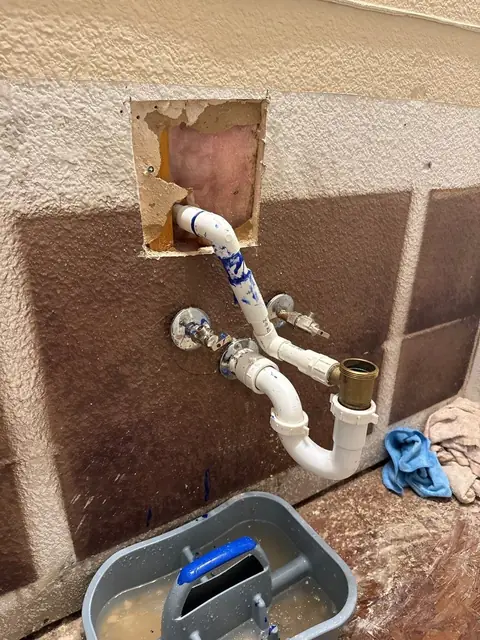 Washer box and drain pipes exposed through a cut-out in a laundry wall