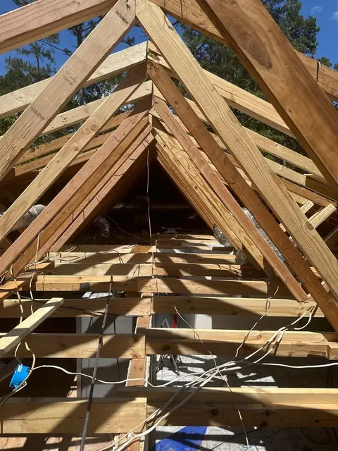 New roof trusses framed against a blue sky after storm damage