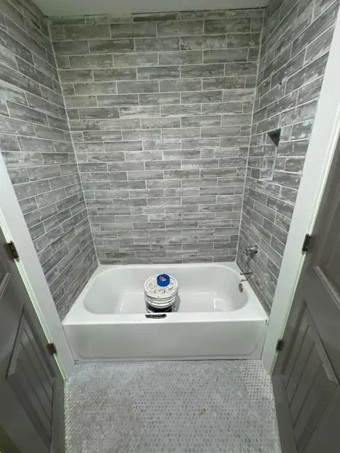 Newly tiled tub surround in gray plank tile