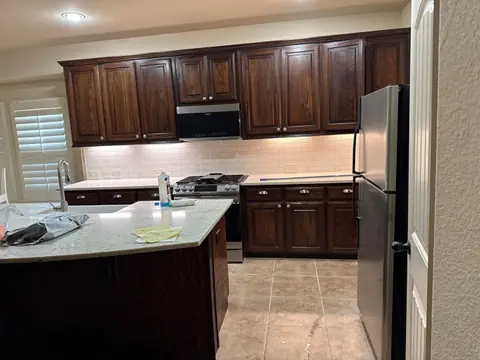 Finished kitchen with dark cabinets, stone counters and new wood floor