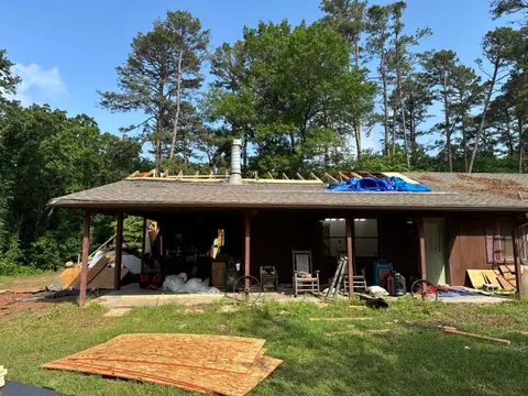 Ranch house with the roof being reframed and partly tarped