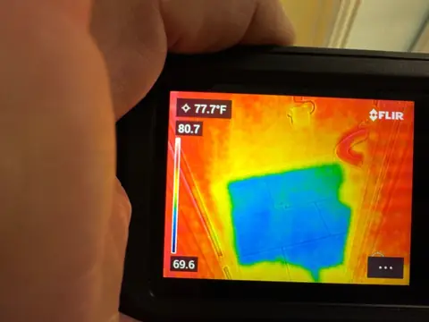 Thermal camera screen showing a cold blue patch of wet flooring